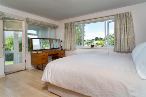 um quarto com uma cama, uma secretária e janelas em Palace Park Manorbier em Manorbier