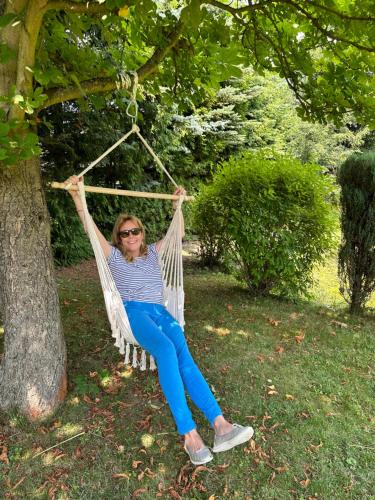 kobieta siedząca w hamaku pod drzewem w obiekcie Serenity Garden Villas - Polanica-Zdrój 