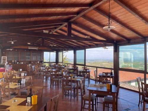 un ristorante con tavoli e sedie in legno e finestre di Albergo Diffuso Belvedere ad Alice Bel Colle