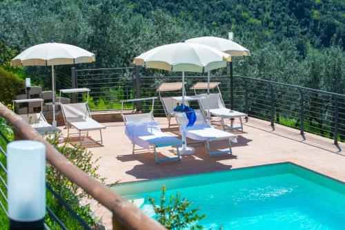 patio z leżakami i parasolami oraz basenem w obiekcie Le Terrazze di Cancellara w mieście Foligno