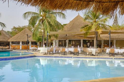 una piscina con mesas y sillas junto a un complejo en Hotel Royam, en Saly Portudal