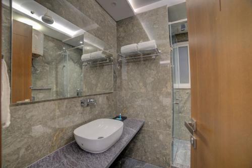 新德里的住宿－Hotel Exotica Suites Near AIIMS，一间带卫生间和玻璃淋浴间的浴室