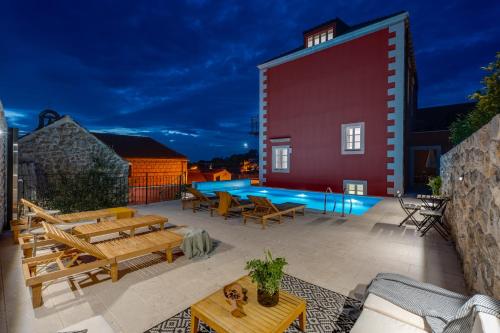 a patio with wooden benches and a swimming pool at Cavtat Old School in Cavtat