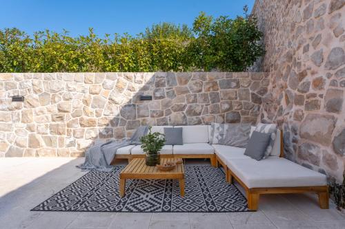 a patio with couches and a table and a stone wall at Cavtat Old School in Cavtat