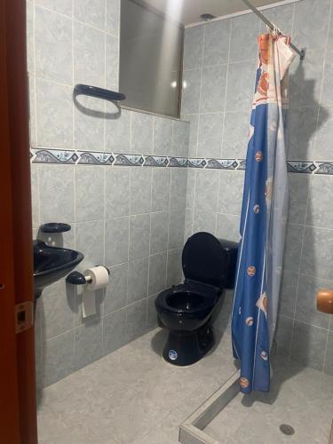 baño con aseo y cortina de ducha azul en Apartamento Santa Rosa de Viterbo en Santa Rosa de Viterbo
