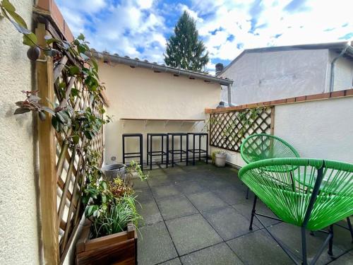 - une terrasse avec 2 chaises vertes et un bâtiment dans l'établissement Maison Verdun Centre 