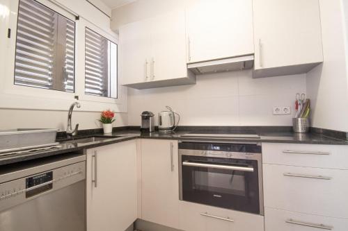 a white kitchen with white cabinets and appliances at La Galera in Torredembarra