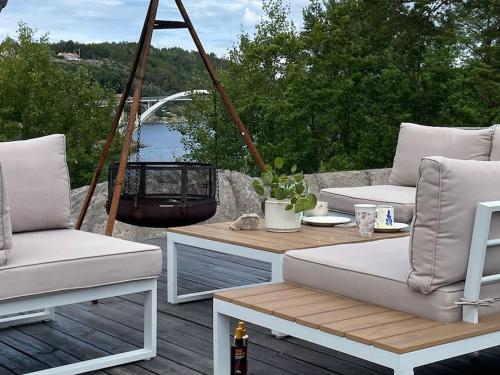 un patio con muebles blancos, mesa y sillas en Summerhouse in south of Norway with privat boat house. en Arendal