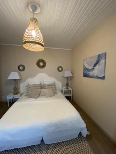 een slaapkamer met een wit bed en een lamp bij Le Chalet de Malo in Biscarrosse