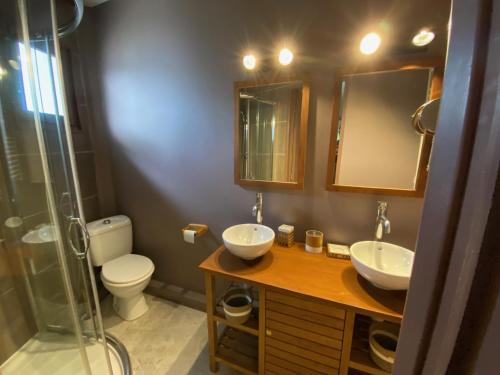 een badkamer met 2 wastafels, een toilet en een douche bij Le Chalet de Malo in Biscarrosse