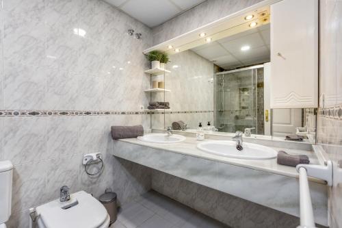 a bathroom with two sinks and a toilet and a mirror at 200m from the beach Apartment San Pedro Marbella in Marbella