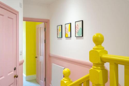 a yellow railing in a room with paintings on the wall at Stunning Broadstairs 5 bed Family Hse, Parking, Garden in Kent