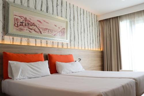 2 bedden in een hotelkamer met oranje kussens bij Eurohotel Barcelona Granvia Fira in Hospitalet de Llobregat