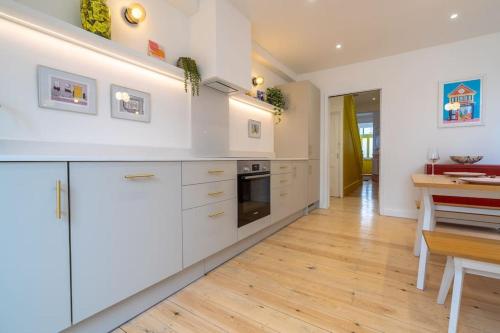 a kitchen with white cabinets and a wooden floor at Stunning Broadstairs 5 bed Family Hse, Parking, Garden in Kent
