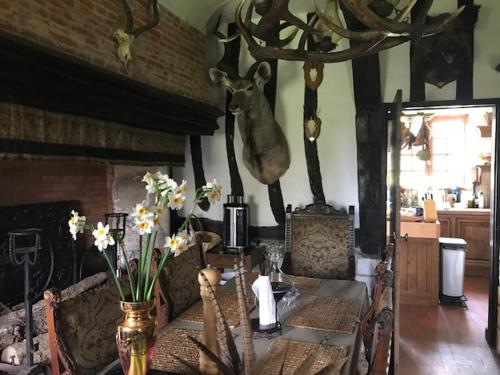 a dining room with a table with a deer head on the wall at The Manor of Vattetot, historical landmark XII-XVI century in Vattetot-sur-Mer