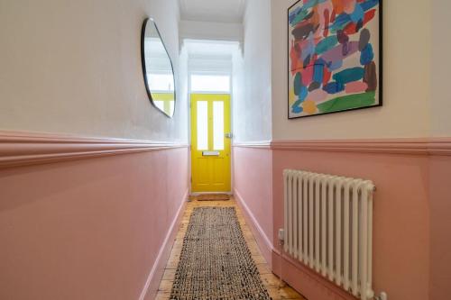 a hallway with a yellow door and a mirror at Stunning Broadstairs 5 bed Family Hse, Parking, Garden in Kent