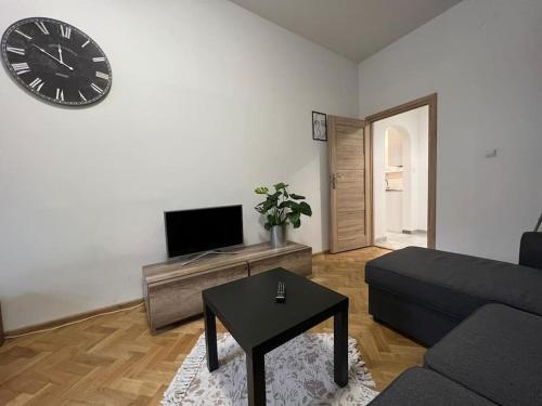 a living room with a couch and a clock on the wall at Heart of Old Town / Floriańska 19 in Krakow