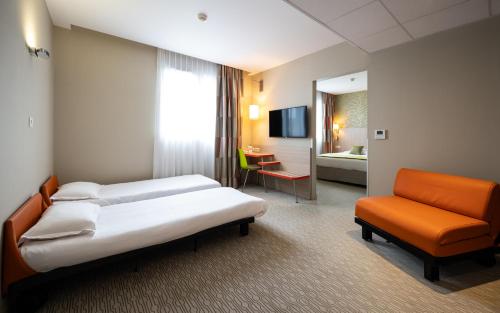 a hotel room with two beds and a chair at Kyriad Prestige Saint-Malo in Saint Malo