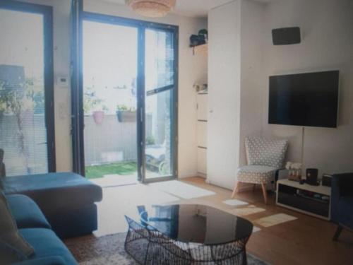 ein Wohnzimmer mit einem blauen Sofa und einem großen Fenster in der Unterkunft Appartement Montreuil 60M2 - Idéal JO Paris 2024 in Montreuil