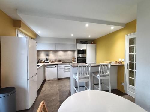 een keuken met een witte koelkast en 2 witte stoelen bij Appartement et Maison Espace Mayenne in Laval