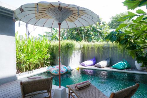 Tropical Beach House Bali في سمينياك: فناء فيه مظله ومسبح