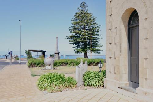 a stone building with a tree in a park at The Customs House Port MacDonnell in Port MacDonnell