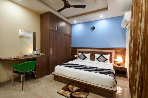 a bedroom with a bed and a desk with a green chair at The Indian Hotel Near Medanta Hospital in Gurgaon