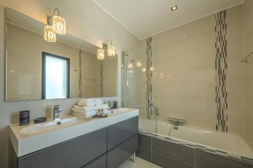 une salle de bain avec un lavabo, une baignoire et un miroir dans l'établissement Villa Les Arbousiers - Piscine Chauffée Sécurisée - 210m2 - 4 Suites, à Porto-Vecchio