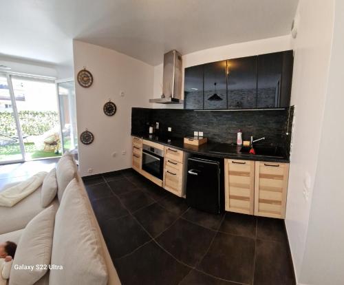 - une cuisine équipée d'appareils noirs et un canapé dans la chambre dans l'établissement Appartement cosy proche du stade et de la plage, à Marseille