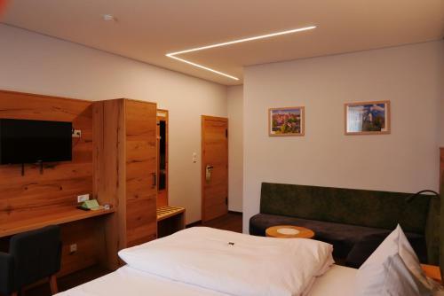 a bedroom with a bed and a couch and a television at Hotel Gasthof Hereth in Wirsberg