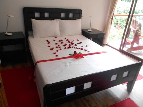 a bed with a bunch of red roses on it at Cashew Nut Grove Chalets in Port Glaud