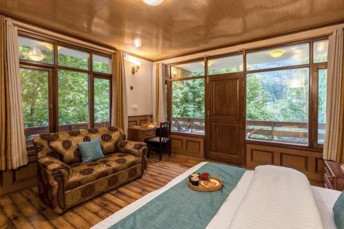 un soggiorno con divano e alcune finestre di Bear Creek: Luxury 2BHK Cottage near Mall Road a Manāli