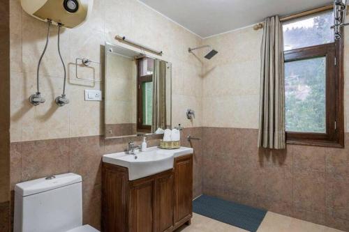 a bathroom with a sink and a toilet and a mirror at Bear Creek: Luxury 2BHK Cottage near Mall Road in Manāli