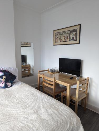 a bedroom with a bed and a desk with a television at Tottenham Stadium Rooms 1 in London