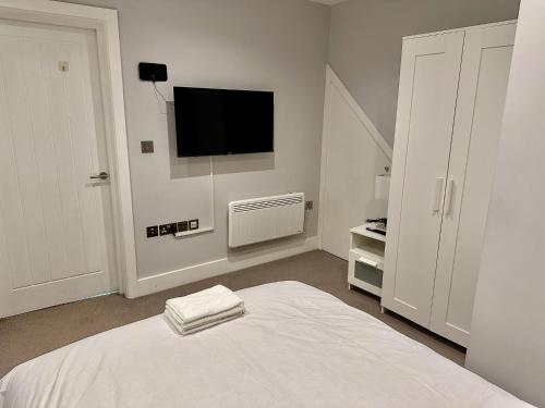 a white bedroom with a bed and a flat screen tv at Upminster Bridge Station Excel House in Hornchurch