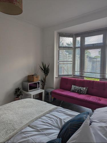 a bedroom with a purple couch and a window at Tottenham Stadium Rooms 1 in London