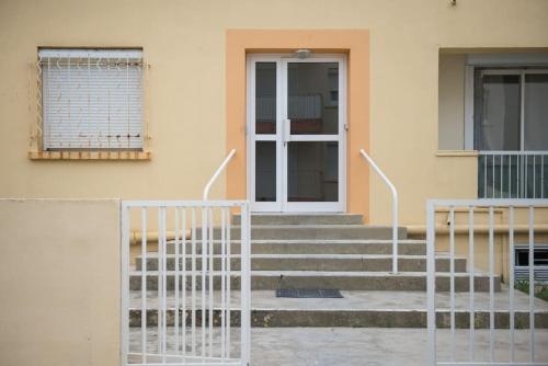 ein Gebäude mit einer weißen Tür und einer Treppe vorne in der Unterkunft appartement 2 chambre, plage à 50m in Palavas-les-Flots