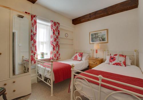 two beds in a bedroom with red and white curtains at South Flat in Wells next the Sea