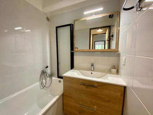 a bathroom with a sink and a tub and a mirror at La Citadelle du Soleil in Le Grau-du-Roi