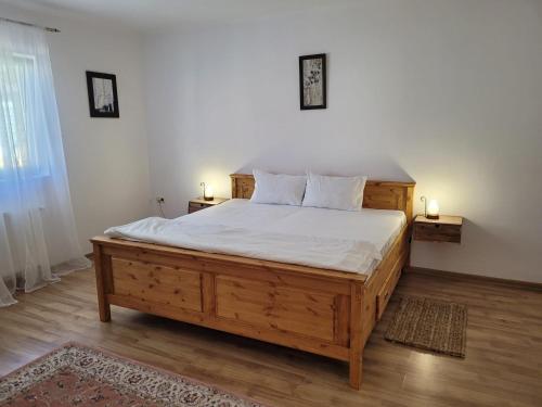 - une chambre avec un grand lit en bois et des draps blancs dans l'établissement Gabi's home #1, à Sighişoara