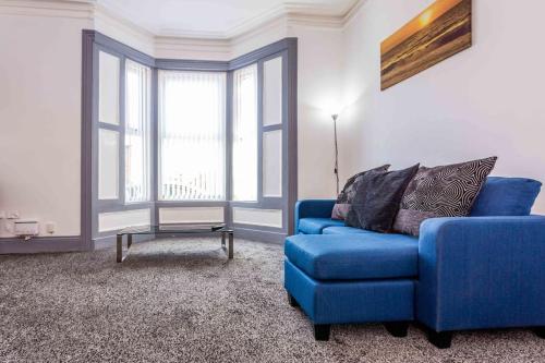 a living room with a blue couch and a window at Guest Homes - Bambro Flat in Sunderland