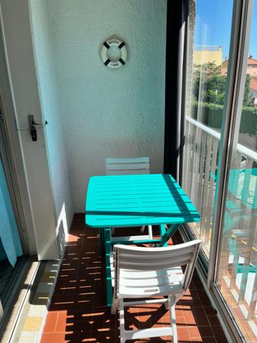 une table bleue et deux chaises sur un balcon dans l'établissement Studio Aquarium Canet, à Canet