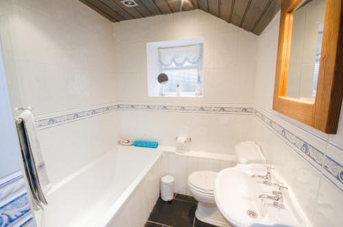 a bathroom with a tub and a toilet and a sink at Tal y Gaer Cottage Goodwick in Saint Nicholas