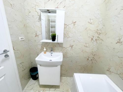een witte badkamer met een wastafel en een spiegel bij Central Adress CD22 in Boekarest
