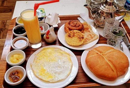 un tavolo in legno con piatti per la colazione e una bevanda di Tommy Tour Sahara a Dakhla