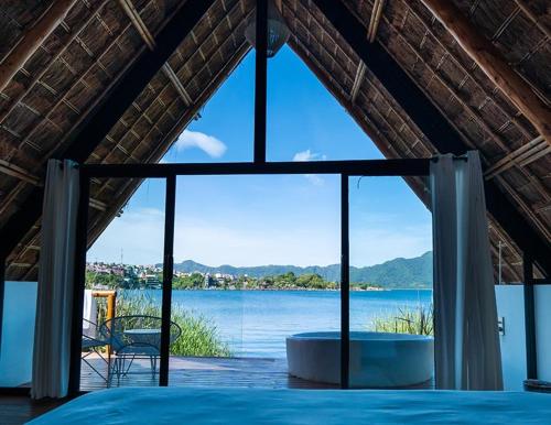 a room with a large window with a view of the water at Hotel Bambu in Santiago Atitlán