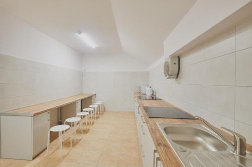 a kitchen with a sink and a row of stools at Hostel L44 in Nowy Targ