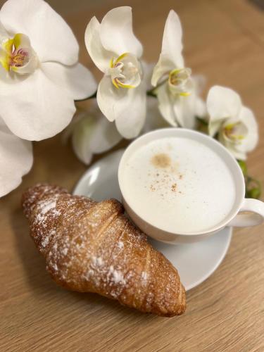 a cup of coffee and a pastry on a plate with flowers at Hotel KOZÁK in Brno