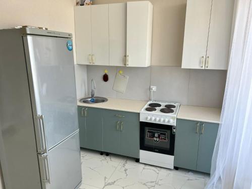 uma pequena cozinha com armários azuis e um frigorífico em Altyn Dala em Taldykolʼ