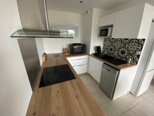 une cuisine avec des armoires blanches et un four à plaques de cuisson dans l'établissement Superbe Appartement centre Sautron, à Sautron